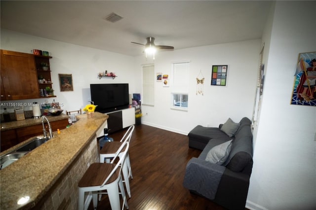living area featuring a ceiling fan, dark wood-style flooring, visible vents, and baseboards