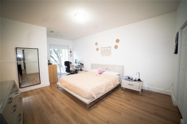 bedroom featuring light wood-style floors, visible vents, and baseboards