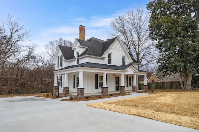 view of front of house with stone siding, metal roof, covered porch, a standing seam roof, and fence