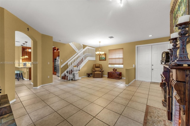 foyer entrance with arched walkways, stairway, baseboards, and light tile patterned floors