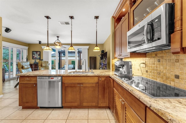 kitchen with stainless steel appliances, a peninsula, a sink, visible vents, and brown cabinetry