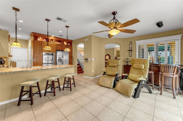 living area with ceiling fan, visible vents, arched walkways, and light tile patterned flooring