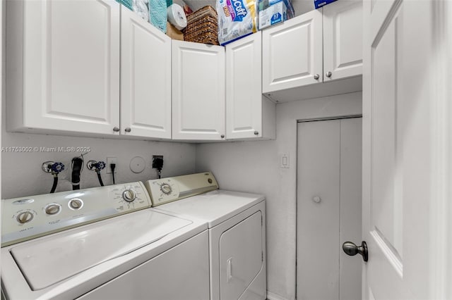 clothes washing area featuring washing machine and dryer and cabinet space