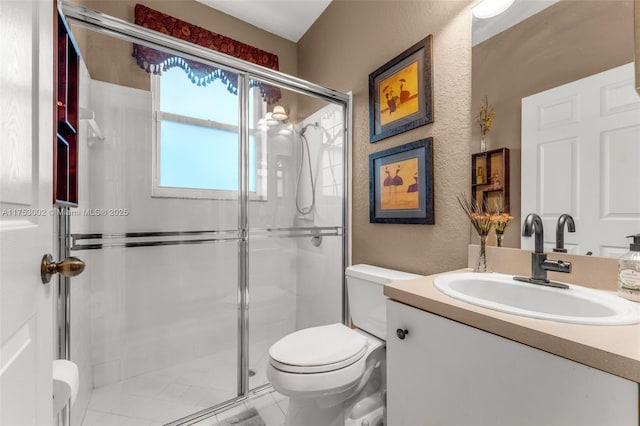 bathroom with toilet, a stall shower, a textured wall, and vanity