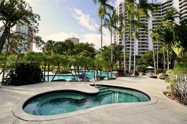 community pool with a patio and a hot tub