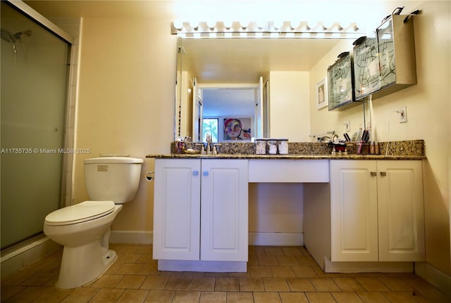 full bathroom featuring double vanity, a stall shower, baseboards, toilet, and a sink