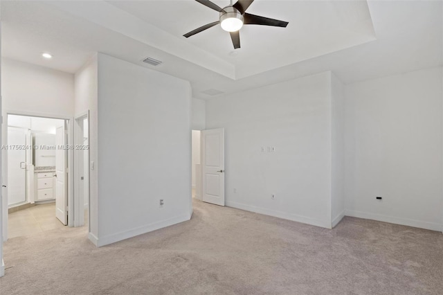 unfurnished bedroom featuring visible vents, connected bathroom, baseboards, light carpet, and a raised ceiling