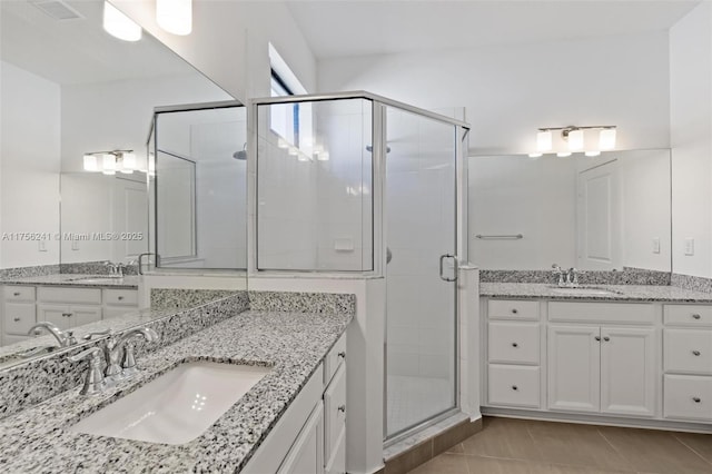 full bathroom featuring two vanities, a stall shower, and a sink