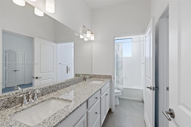 bathroom with tile patterned flooring, double vanity, toilet, and a sink