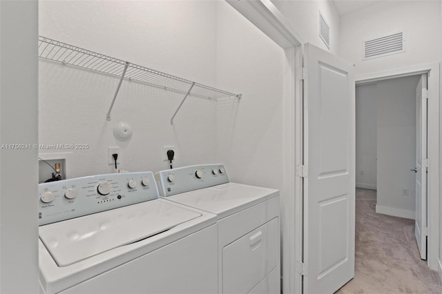 laundry area with light carpet, laundry area, washing machine and dryer, and visible vents