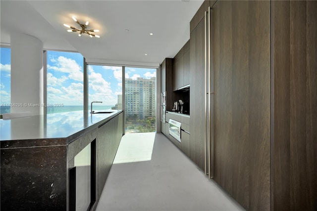 kitchen featuring a view of city, light countertops, a sink, modern cabinets, and a wall of windows