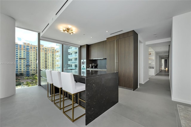 kitchen featuring a city view, a kitchen island, modern cabinets, a wall of windows, and a kitchen breakfast bar