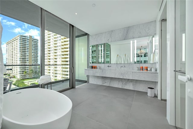 full bath with a wall of windows, a wealth of natural light, a freestanding tub, and a city view