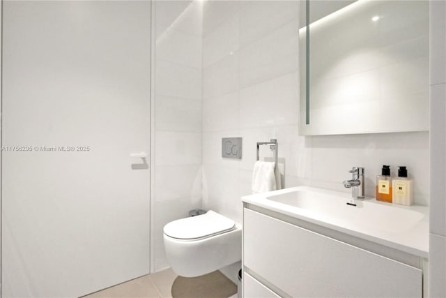 bathroom with toilet, tile patterned flooring, tile walls, and vanity