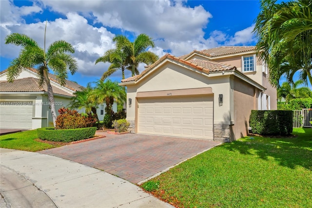 mediterranean / spanish-style house featuring a garage, a tiled roof, decorative driveway, stucco siding, and a front lawn