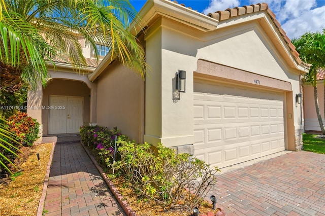 4471 Foxtail Ln, Weston, FL 33331 - view of front of house featuring stucco siding, a garage, a tiled roof, and decorative driveway