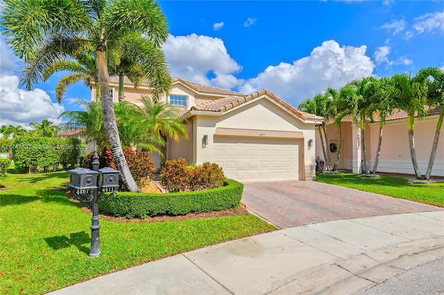 mediterranean / spanish house with a garage, a tiled roof, decorative driveway, stucco siding, and a front lawn