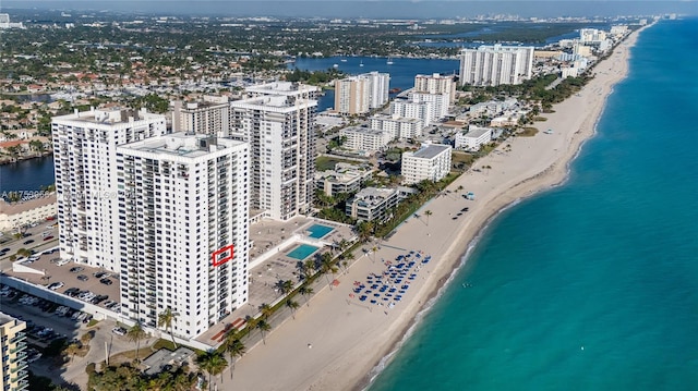 drone / aerial view featuring a water view, a city view, and a beach view