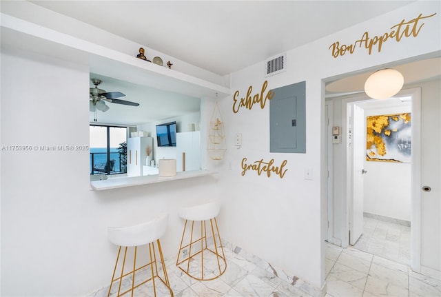 kitchen featuring visible vents, a breakfast bar area, electric panel, freestanding refrigerator, and marble finish floor