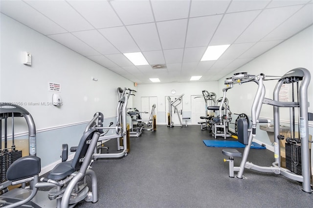 exercise room with baseboards and a drop ceiling