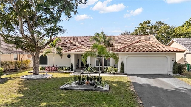 mediterranean / spanish-style home with aphalt driveway, stucco siding, a front lawn, and a garage