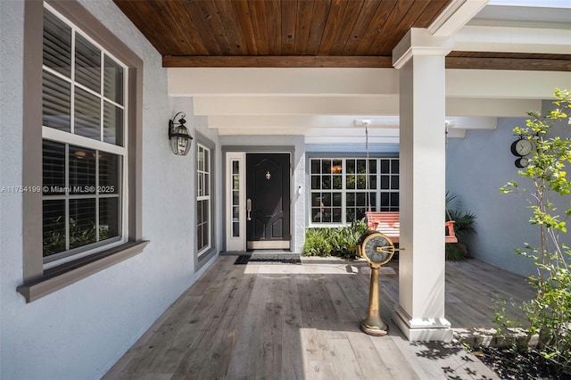 view of exterior entry with covered porch and stucco siding