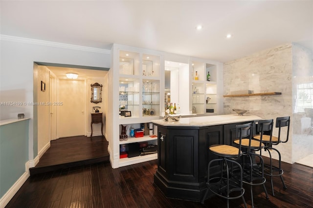 bar with built in features, dark wood finished floors, a dry bar, ornamental molding, and baseboards