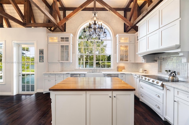 kitchen featuring cooktop, butcher block countertops, dark wood-type flooring, a center island, and white cabinetry