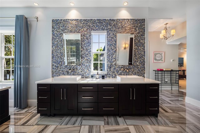 full bath with tasteful backsplash, plenty of natural light, a sink, and double vanity