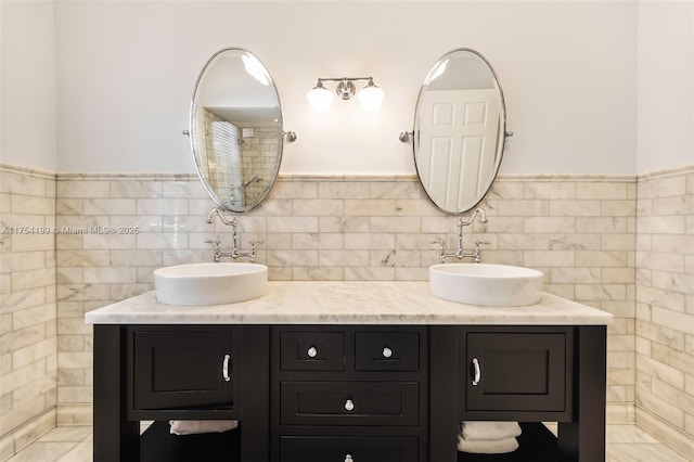 bathroom featuring double vanity, a sink, and tile walls