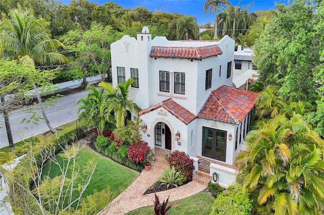 mediterranean / spanish house with a tiled roof, french doors, and stucco siding