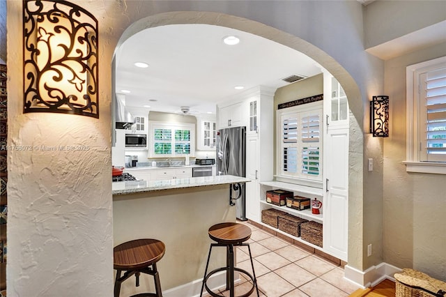 kitchen with white cabinets, appliances with stainless steel finishes, arched walkways, and a sink