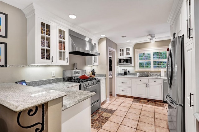 kitchen with stainless steel appliances, white cabinetry, a sink, a peninsula, and wall chimney exhaust hood