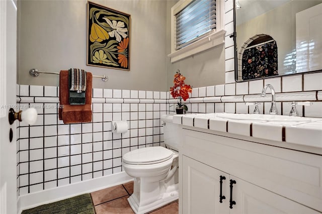 bathroom with a wainscoted wall, tile walls, toilet, vanity, and tile patterned flooring