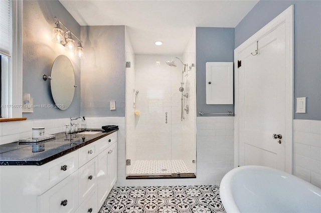 full bathroom featuring a stall shower, a freestanding bath, tile walls, and vanity