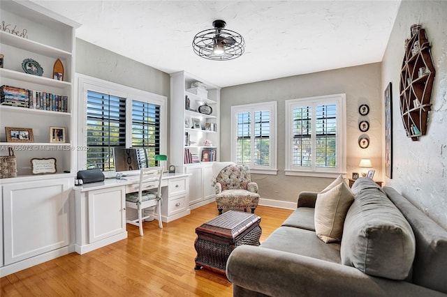 office with built in features, a textured wall, light wood-style flooring, and baseboards