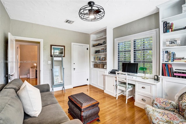 living room with light wood-style flooring, visible vents, and built in features