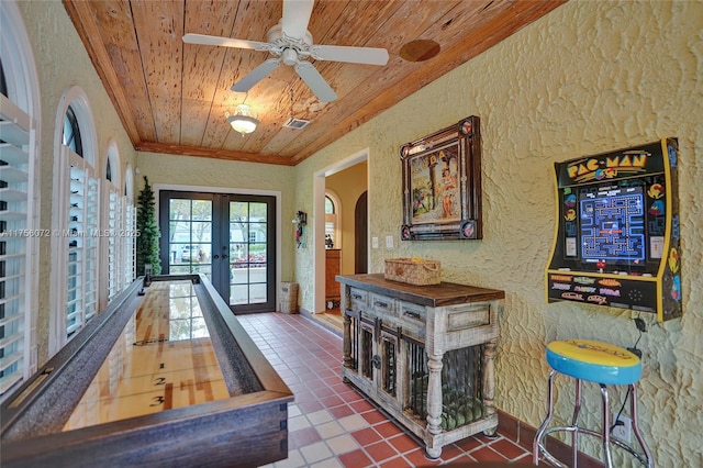 playroom with arched walkways, french doors, a textured wall, ornamental molding, and wooden ceiling