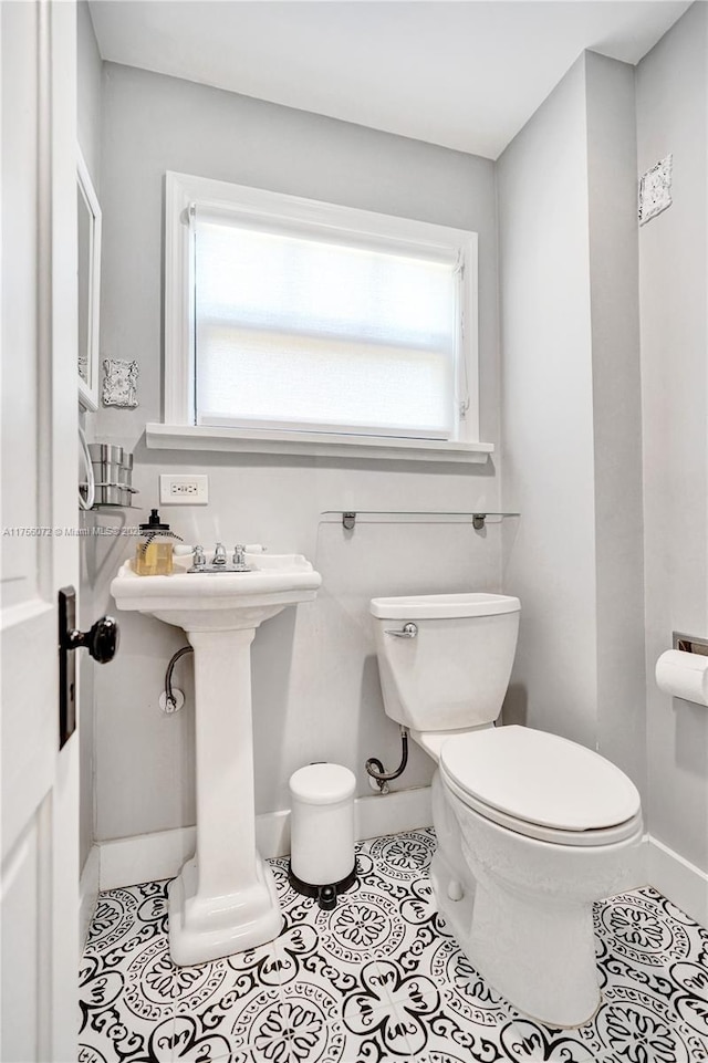 bathroom with baseboards, a sink, toilet, and tile patterned floors