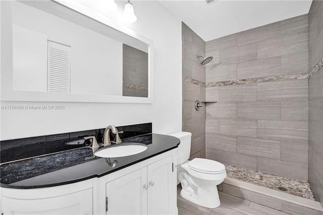 full bath with tiled shower, vanity, and toilet