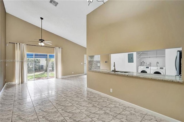 interior space featuring washing machine and dryer, a sink, visible vents, open floor plan, and fridge