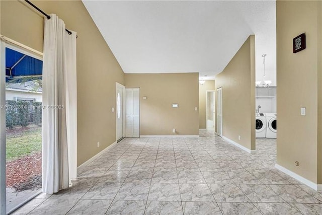 empty room featuring vaulted ceiling, washer and clothes dryer, an inviting chandelier, and baseboards