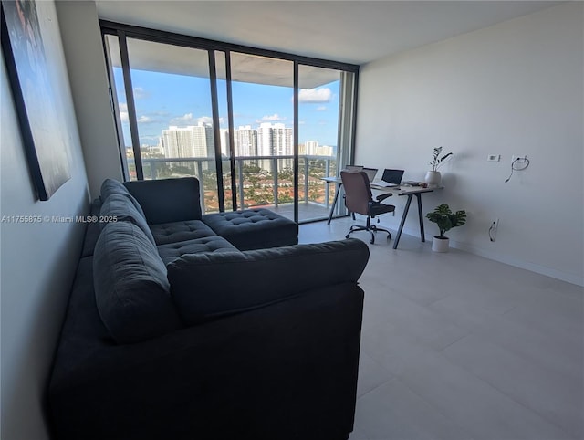 living area featuring baseboards, a wall of windows, and a city view