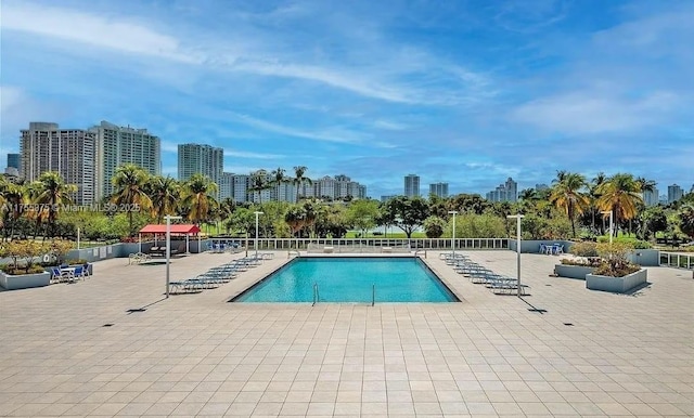 pool featuring a view of city, a patio area, and fence