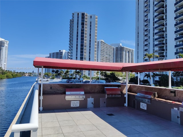 view of patio / terrace with a water view, a view of city, exterior kitchen, and area for grilling