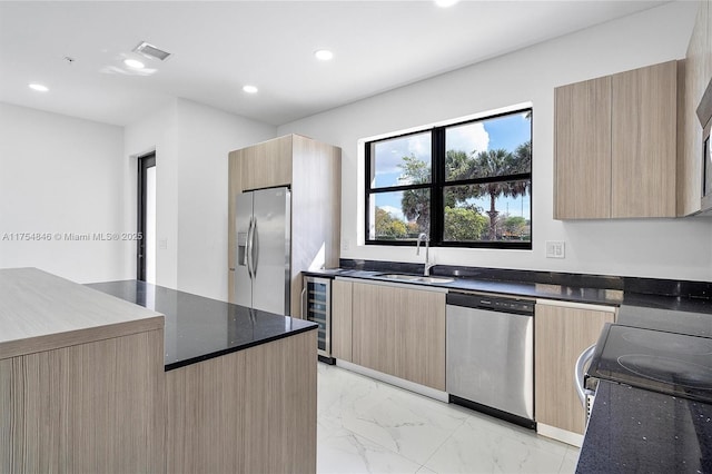 kitchen featuring light brown cabinets, marble finish floor, appliances with stainless steel finishes, and a sink