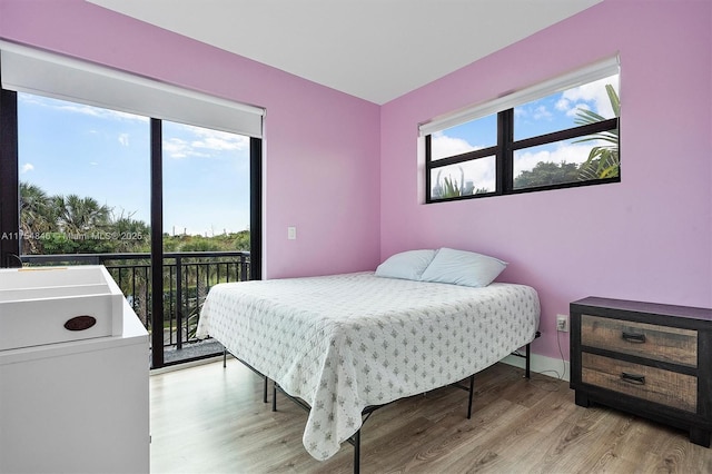 bedroom with access to exterior, baseboards, and wood finished floors