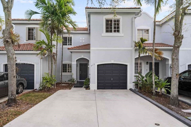 mediterranean / spanish home featuring a garage, a tiled roof, concrete driveway, and stucco siding