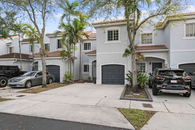 mediterranean / spanish-style home featuring a garage, a tile roof, concrete driveway, and stucco siding