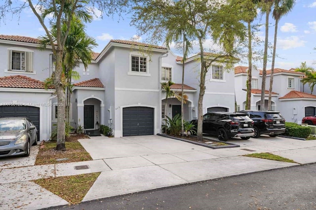 mediterranean / spanish home with driveway, an attached garage, a tiled roof, and stucco siding